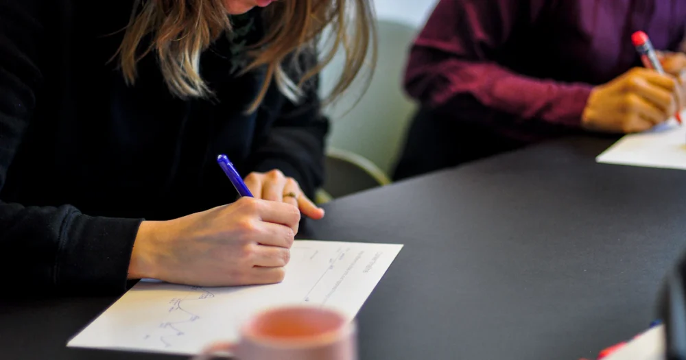 Deltagare som skriver på papper under en workshop